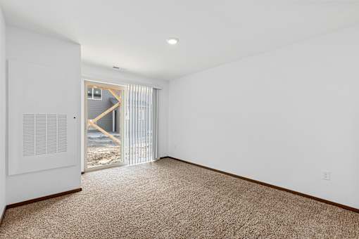 A room with a carpeted floor and a window with blinds.