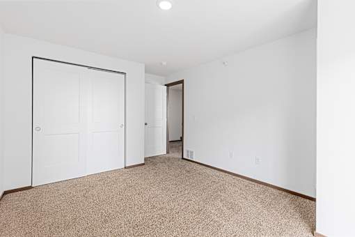 A carpeted room with a white door and a white wall.