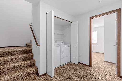 A white closet with a mirror is open to a hallway.