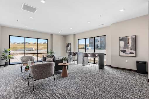 A room with grey carpet and a large window overlooking a field.