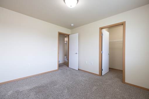 A room with a carpeted floor and two open doors.