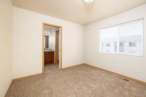 A room with a carpeted floor and a window with blinds.
