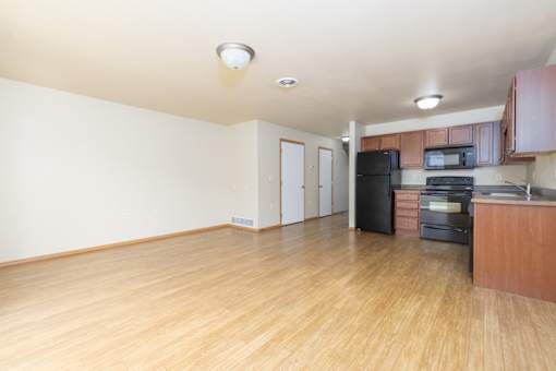A kitchen with wooden floors and a black refrigerator.
