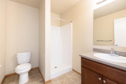A white toilet is in a bathroom with a sink and mirror.