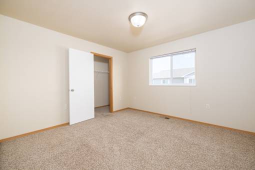 A room with a carpeted floor, a door, and a window.