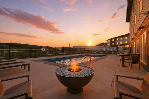 A fire pit sits in the middle of a patio with chairs around it.