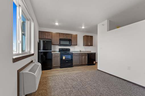 A kitchen with a black fridge, black oven, and a white microwave.