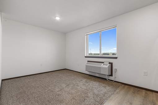 A room with a window and a wall-mounted air conditioner.