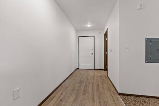 A long hallway with a white door at the end.