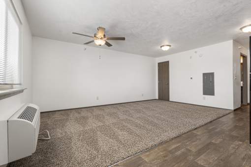 A room with a ceiling fan and a carpet on the floor.