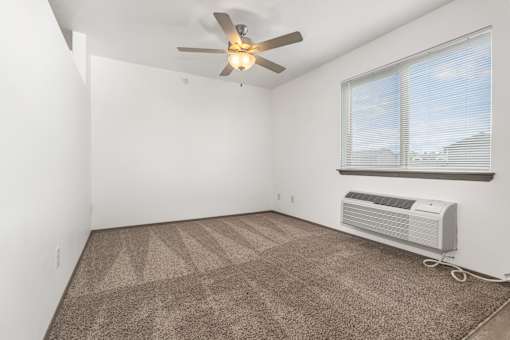 A room with a ceiling fan and a window with blinds.