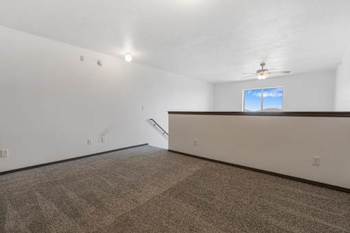 A room with a carpeted floor and a window with a view of the sky.