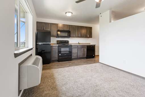 A kitchen with black appliances and brown cabinets.
