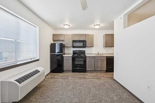 A kitchen with a refrigerator, microwave, oven, and sink.