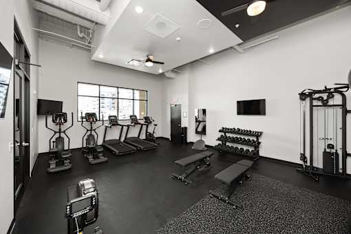 A black and white photo of a gym with various exercise equipment.