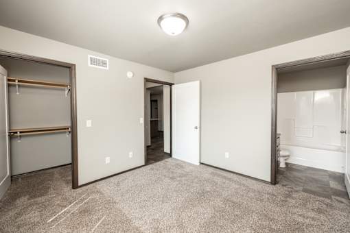 a bedroom with a closet and a bathroom with a mirrored door