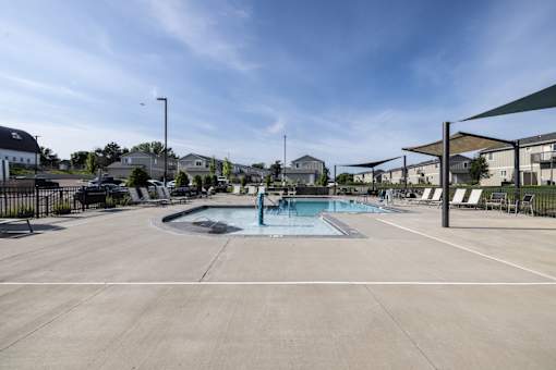 A large outdoor swimming pool with a hot tub and lounge chairs.