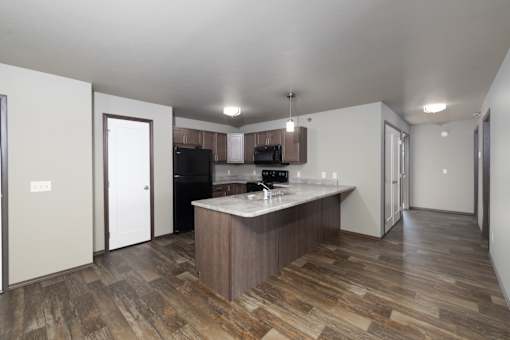 A kitchen with a wooden floor and a white ceiling.