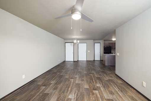 A room with a ceiling fan and wood flooring.