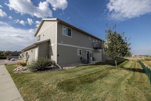 A grey house with a green fence in front.