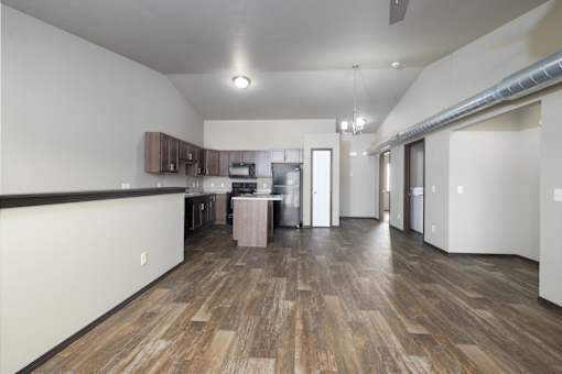 A kitchen with wood flooring and a white wall.