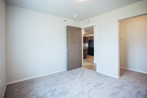 A room with a carpeted floor and a doorway leading to another room.
