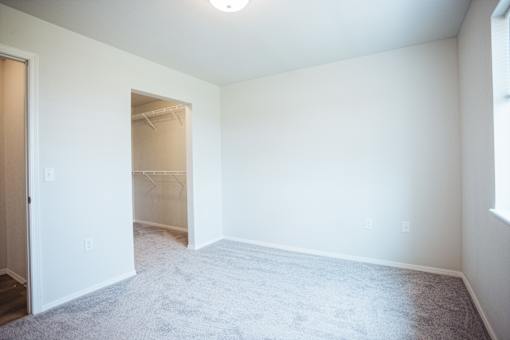 A room with a carpeted floor and a doorway leading to another room.