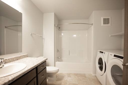 A white bathroom with a sink, toilet, and washing machine.