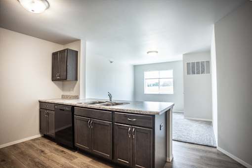 A kitchen with dark wood cabinets and a granite countertop.