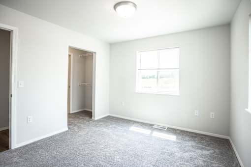 A room with a carpeted floor and a window.