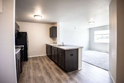 A kitchen with a black fridge and wooden floors.
