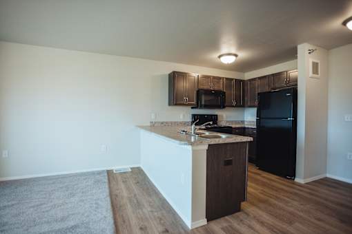 A kitchen with black appliances and wooden cabinets.