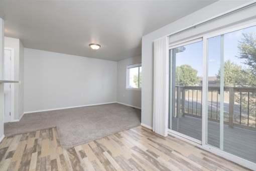 A room with a sliding glass door and wooden flooring.