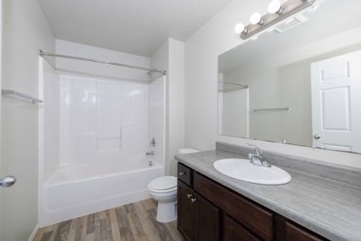 A white bathroom with a toilet, sink, and shower.