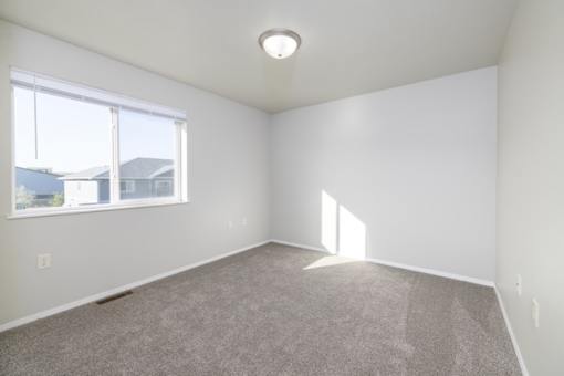 A room with a carpeted floor and a window.