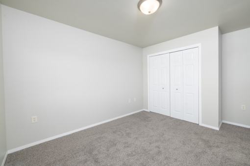 A room with a white door and carpeted floor.