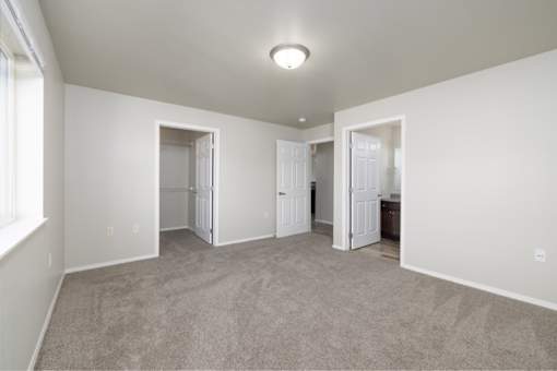 A spacious room with carpeted floor and white walls.
