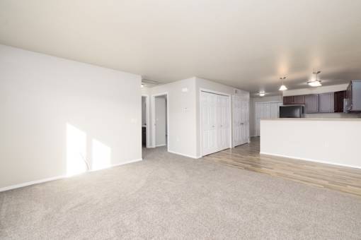 A spacious room with white walls and wooden flooring.