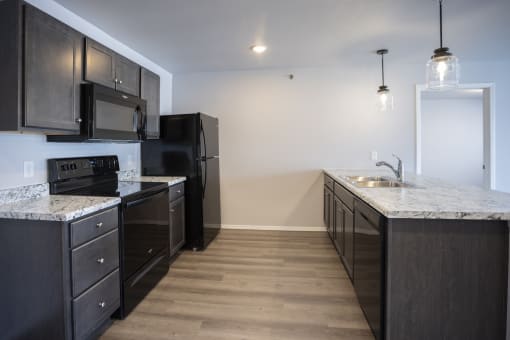 Modern open-concept kitchen and living area with black appliances.