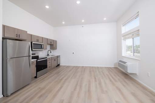 A kitchen with a refrigerator, microwave, oven, and cabinets.