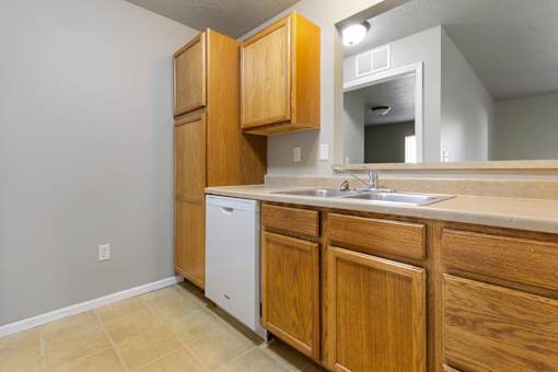 A kitchen with wooden cabinets and a white dishwasher.