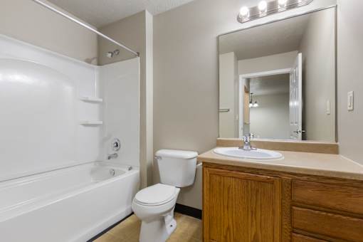 A white toilet sits next to a white bathtub in a bathroom.