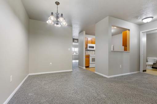 A spacious room with a grey carpet and a chandelier hanging from the ceiling.