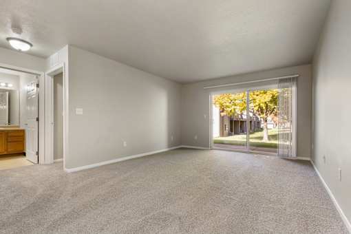 A spacious room with a carpeted floor and a large window.