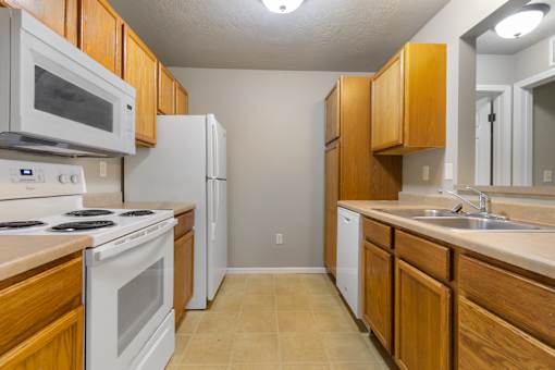 A kitchen with white appliances and wooden cabinets.