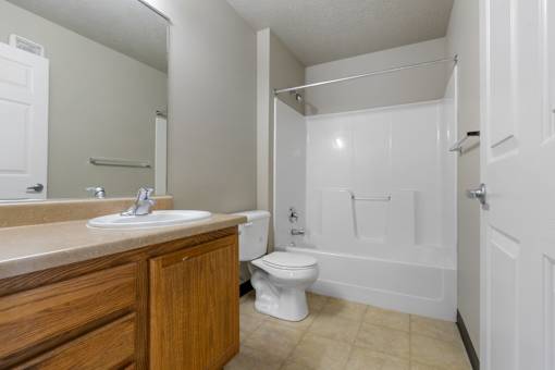 A white toilet is in a bathroom with a sink and a bathtub.