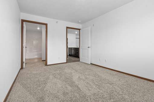 A room with a carpeted floor and two open doors.
