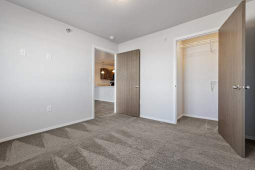 A room with a carpeted floor and a white wall with a doorway leading to another room.