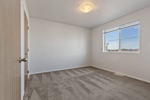 A room with a carpeted floor and a window.
