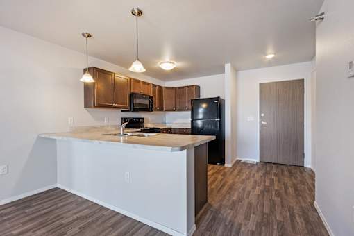 A kitchen with a black fridge and wooden cabinets.